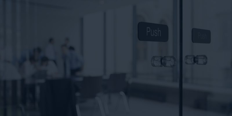 Glass doors in an office with people in a meeting room