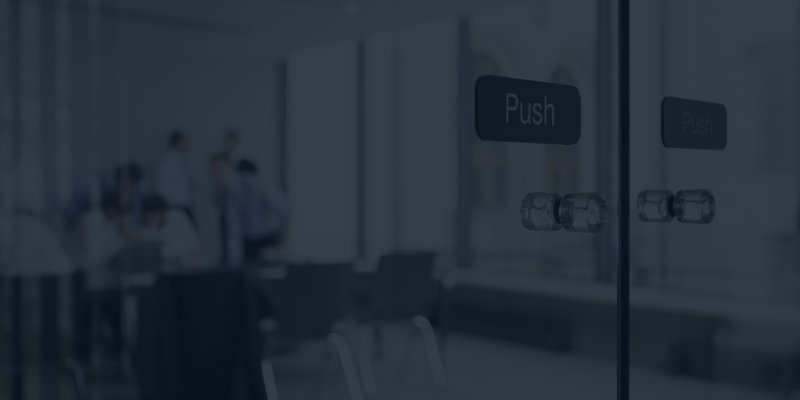 Glass doors in an office with people in a meeting room