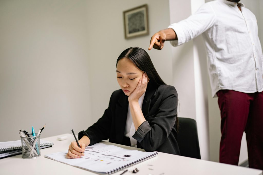 woman under stress working with someone pointing at her
